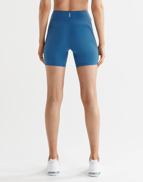 Woman wearing blue bike shorts and white sneakers from the back