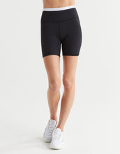 A woman wearing black activewear shorts and white runners.