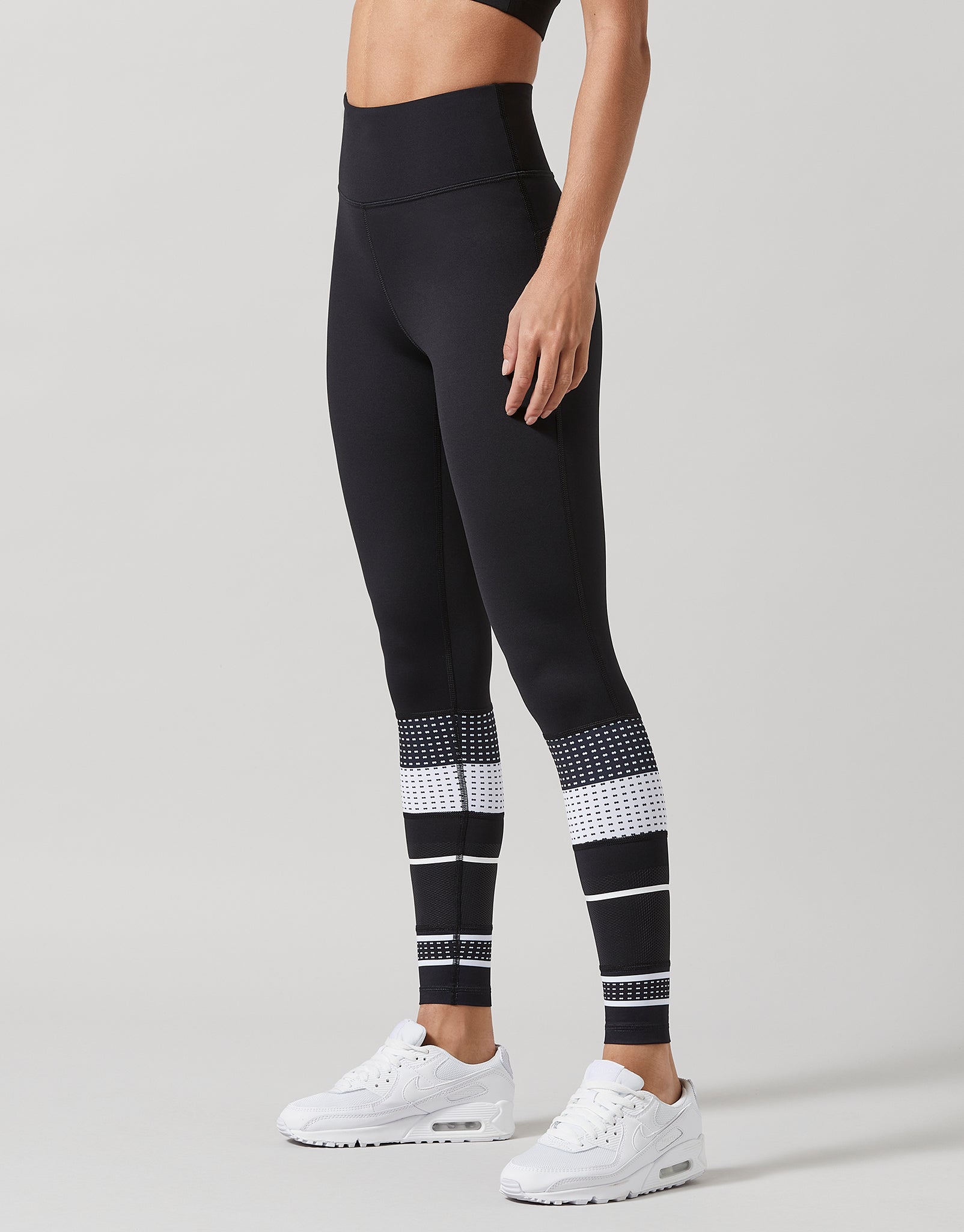 Black leggings with white patterned accents worn by a person on a gray background
