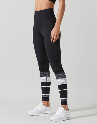 Black leggings with white patterned accents worn by a person on a gray background