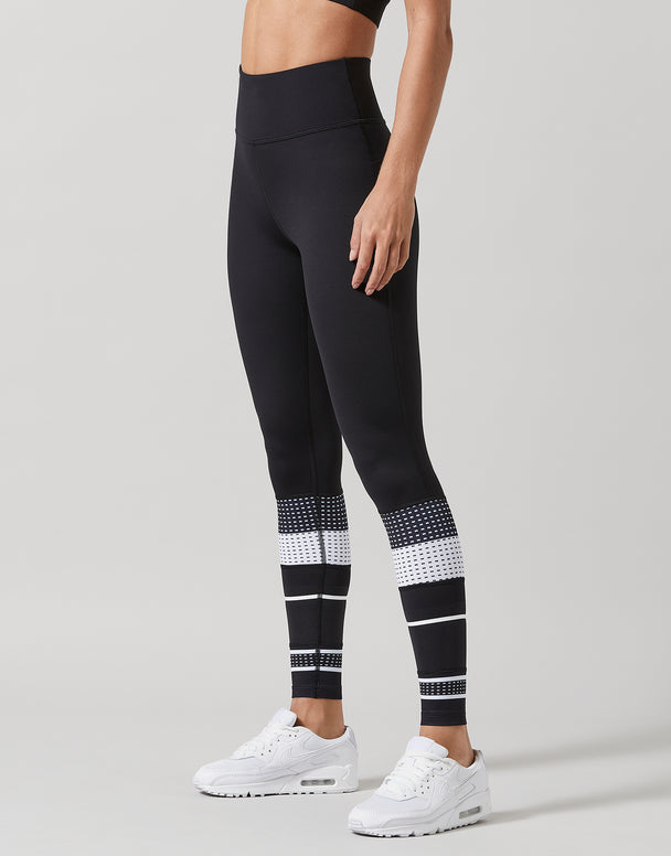 Black leggings with white patterned accents worn by a person on a gray background