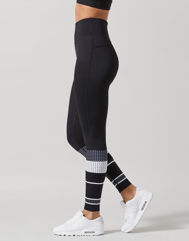 Black leggings with white patterned accents worn by a person on a gray background