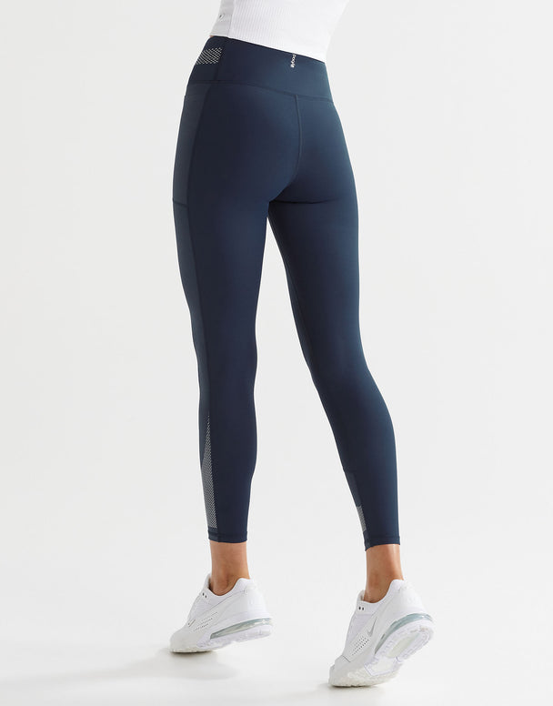 A model wearing navy and white high-waisted leggings with a color-blocked waistband and a printed accent pattern on the legs.