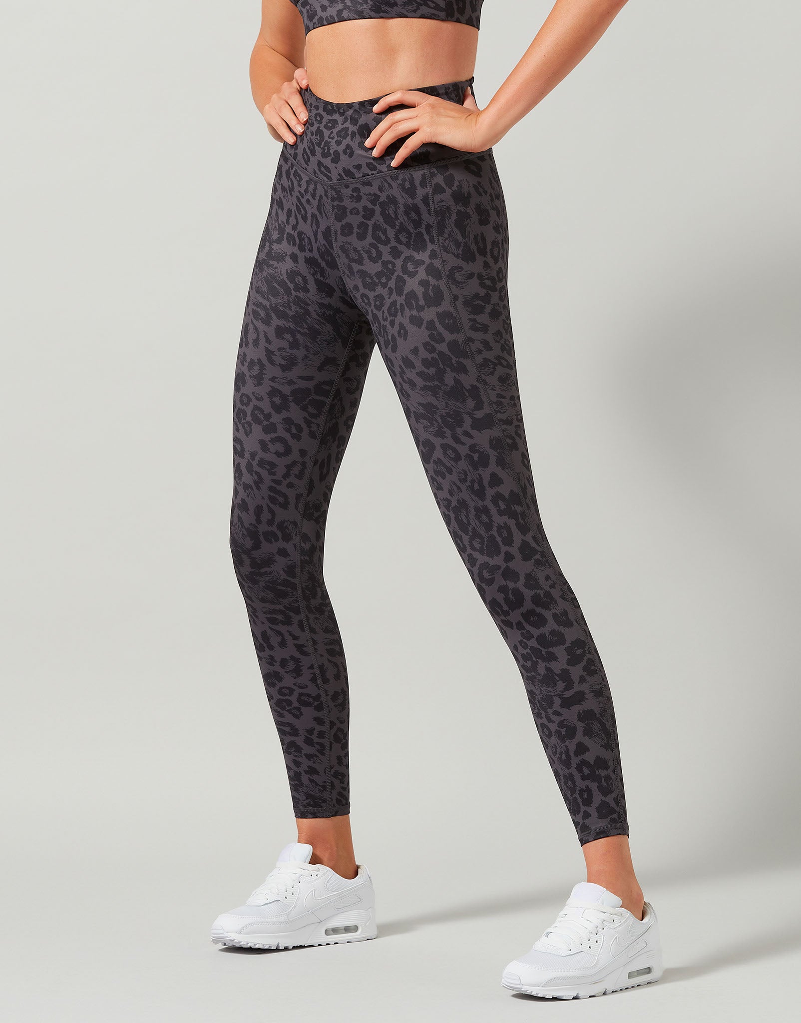 Person wearing black leopard print leggings on a gray background