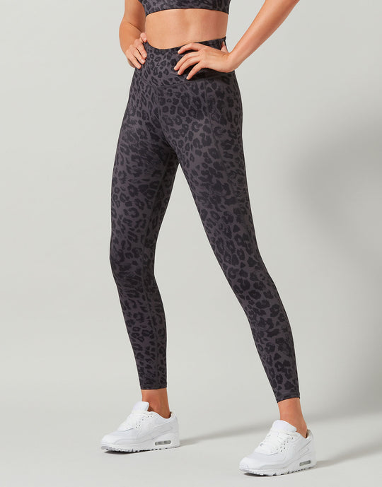 Person wearing black leopard print leggings on a gray background