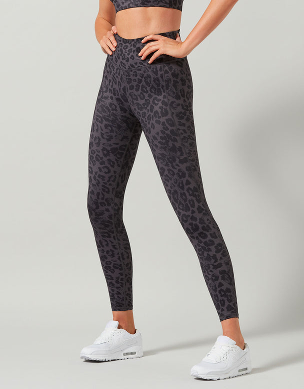 Person wearing black leopard print leggings on a gray background