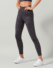 Person wearing black leopard print leggings on a gray background