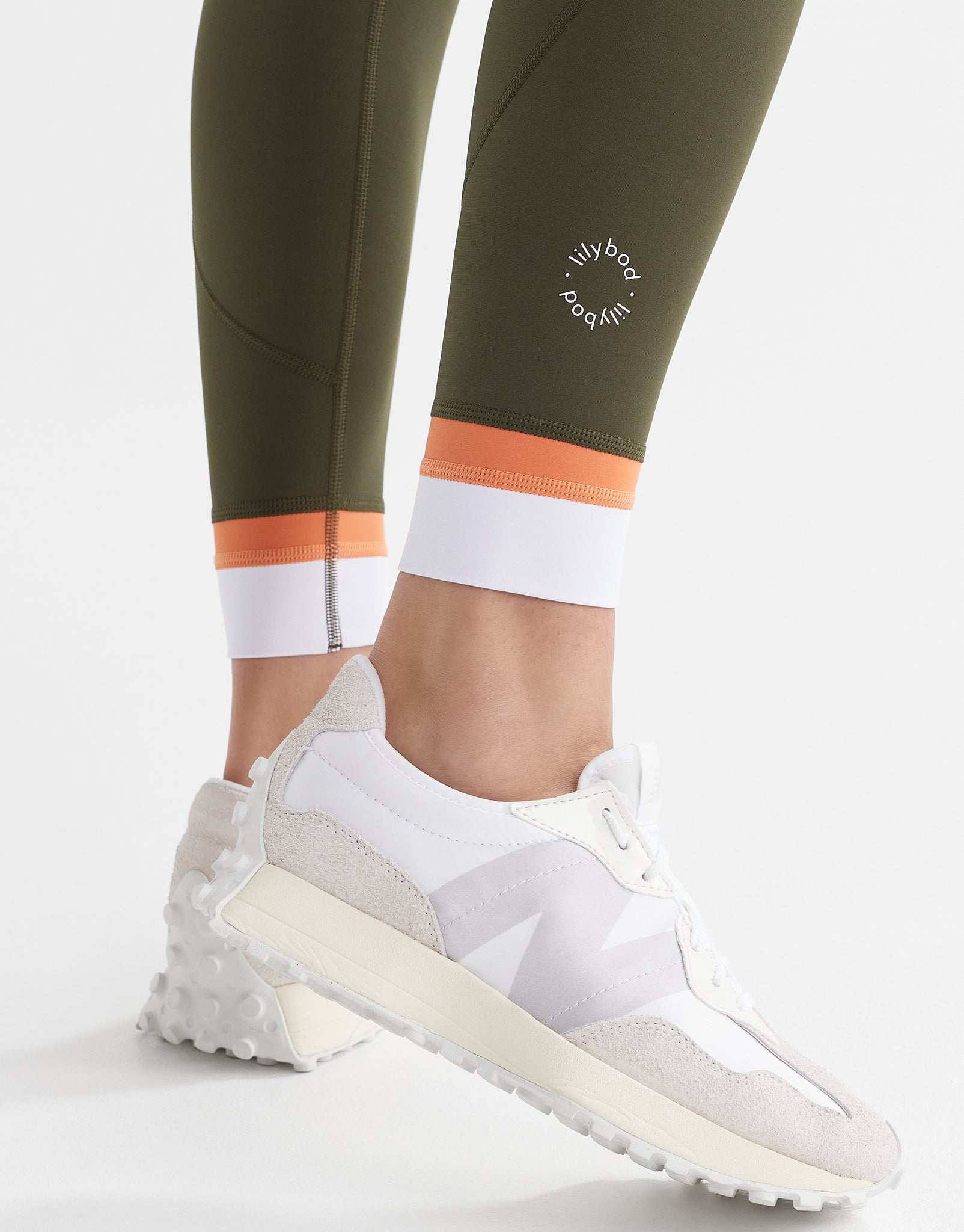 A close up of army green leggings with a white and orange cuff.