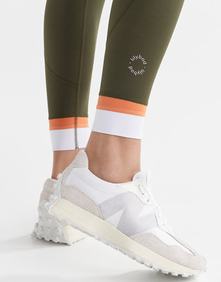 A close up of army green leggings with a white and orange cuff.