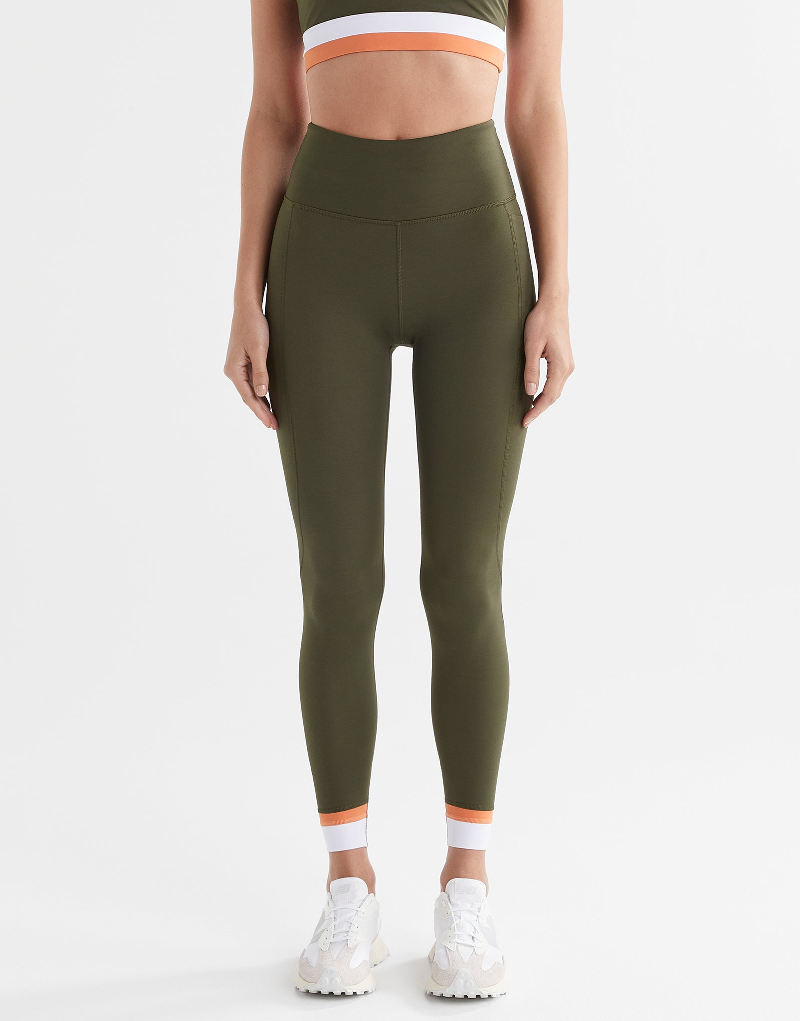 A woman wearing army green leggings with a white and orange cuff.