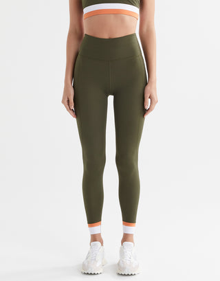 A woman wearing army green leggings with a white and orange cuff.