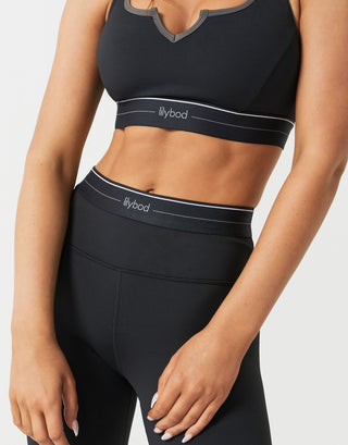 A woman wearing black leggings and a  matching top on a white background.