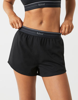 A person wearing black running shorts on a white background.