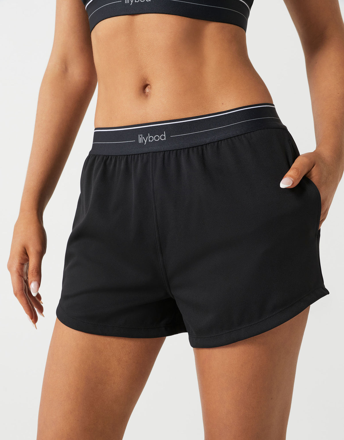 A woman wearing black running shorts on a white background.