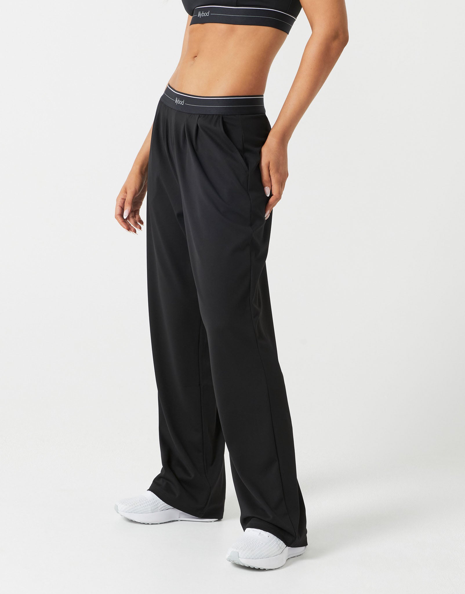 A person wearing black sweatpants and white runners