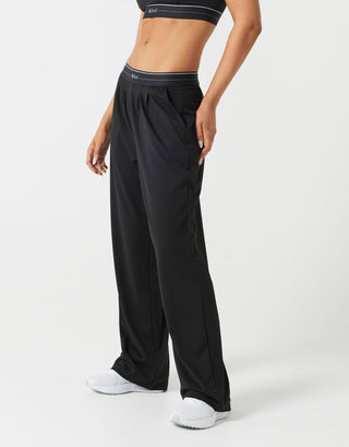 A person wearing black sweatpants and white runners