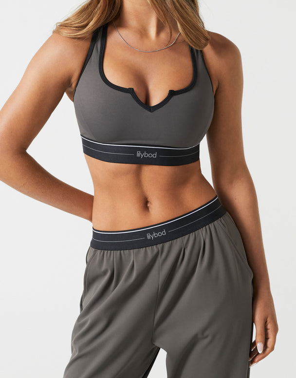 A woman wearing a charcoal sports bra on a white background.
