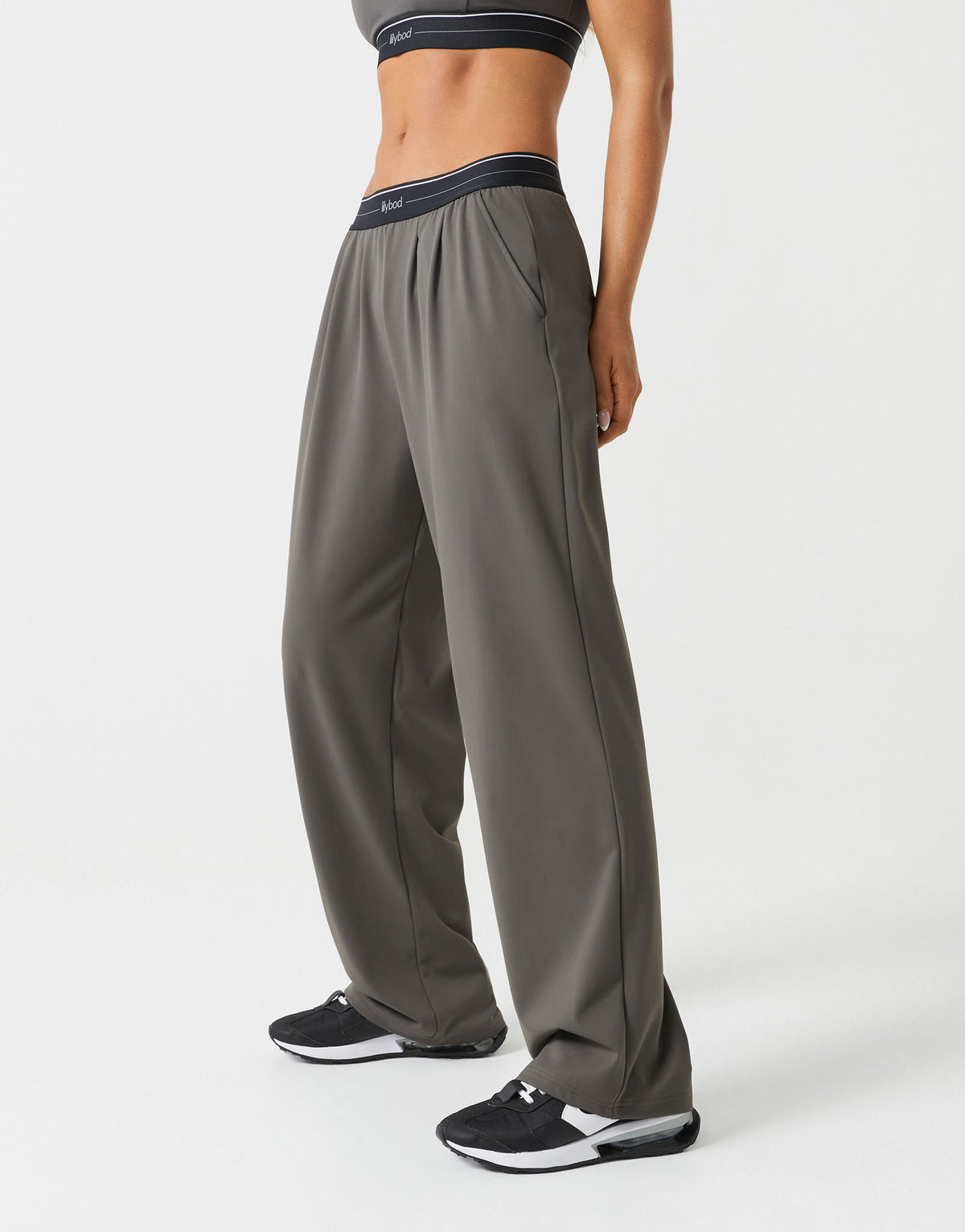 A woman wearing olive green wide leg pants on a white background.