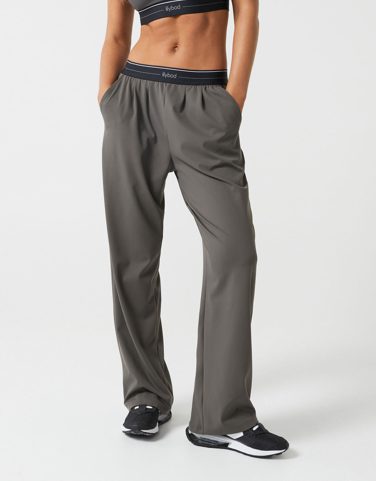 A person wearing olive green wide leg pants on a white background.