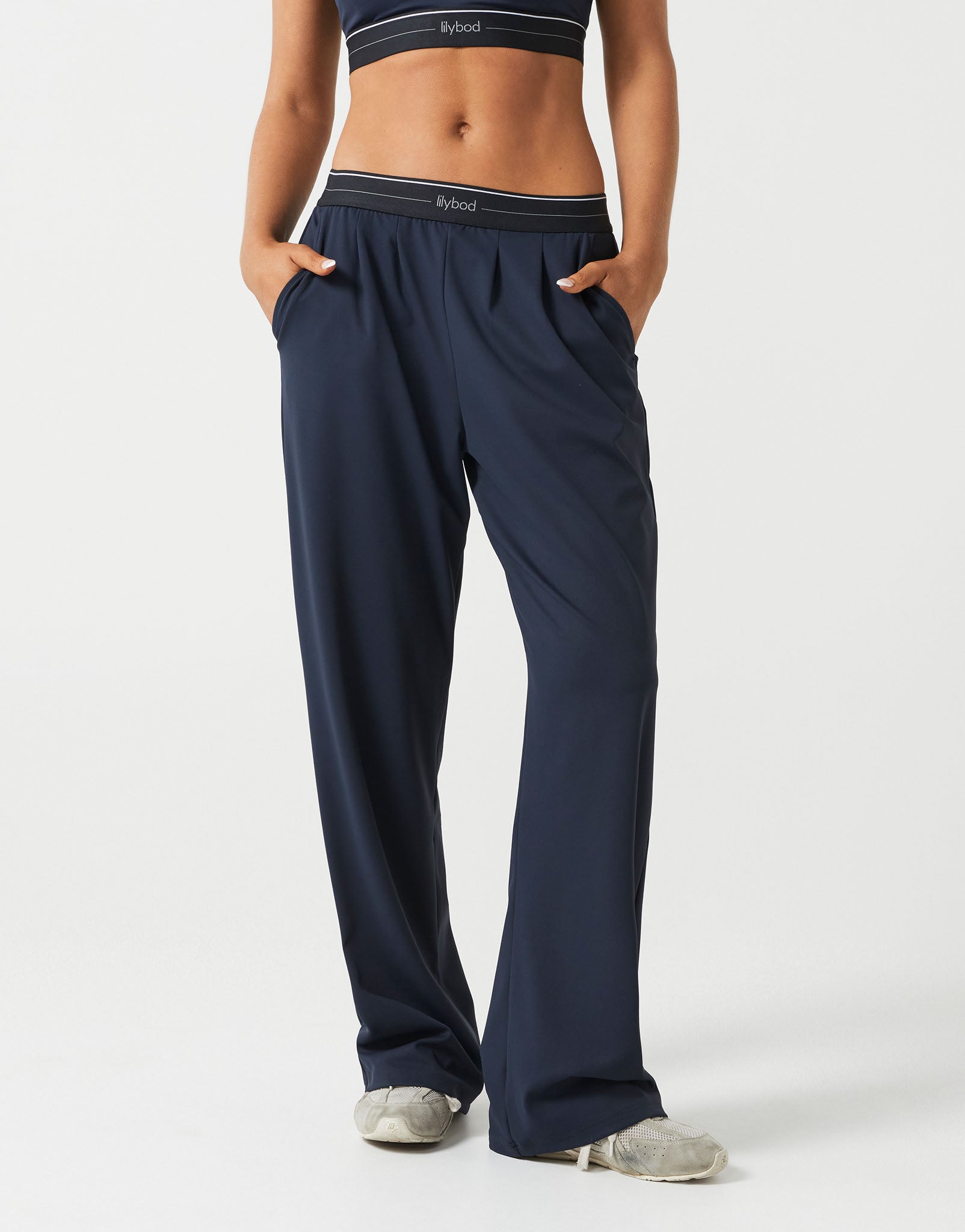 A person wearing dark navy wide leg sweatpants on a white background