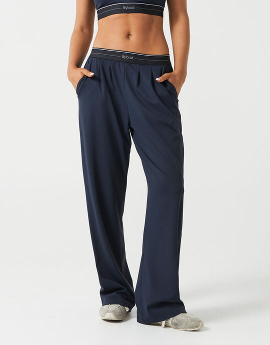 A person wearing dark navy wide leg sweatpants on a white background