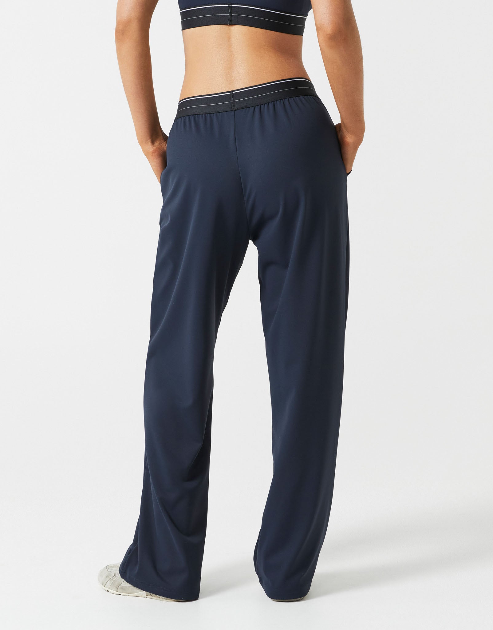 A person wearing dark navy wide leg sweatpants on a grey background