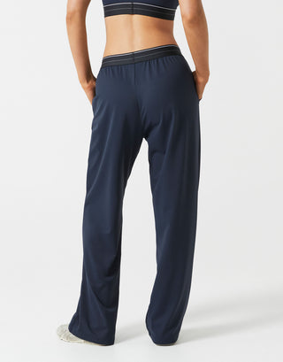 A person wearing dark navy wide leg sweatpants on a grey background