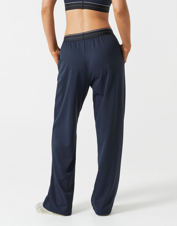 A person wearing dark navy wide leg sweatpants on a grey background