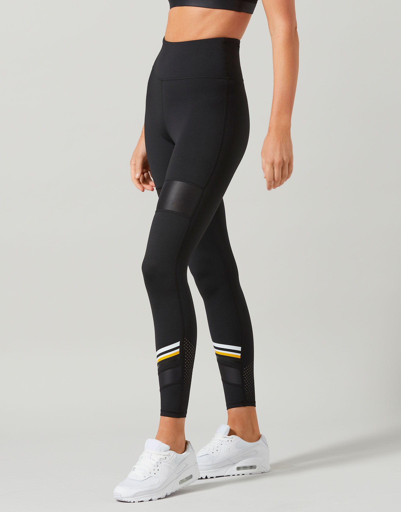 Black leggings with white and yellow accents worn by a person on a light gray background