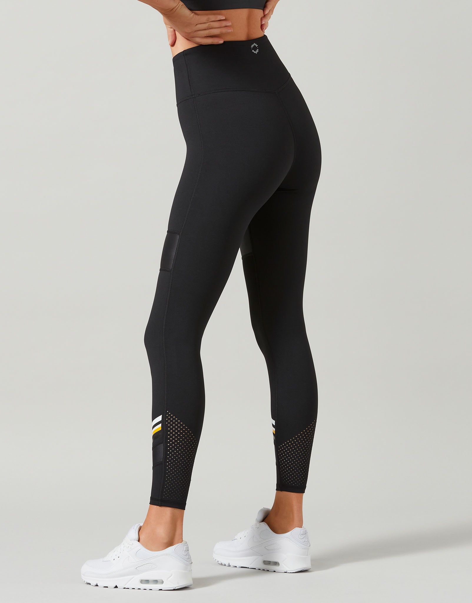 Black leggings with white sneakers on a light gray background