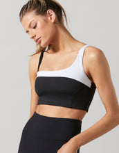 Woman wearing a black and white sports bra on a plain background