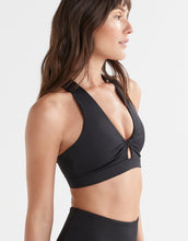 Woman wearing a black sports bra on a plain background