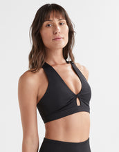 Woman wearing a black sports bra on a plain background