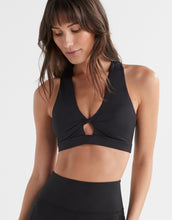 Woman wearing a black sports bra and leggings on a white background