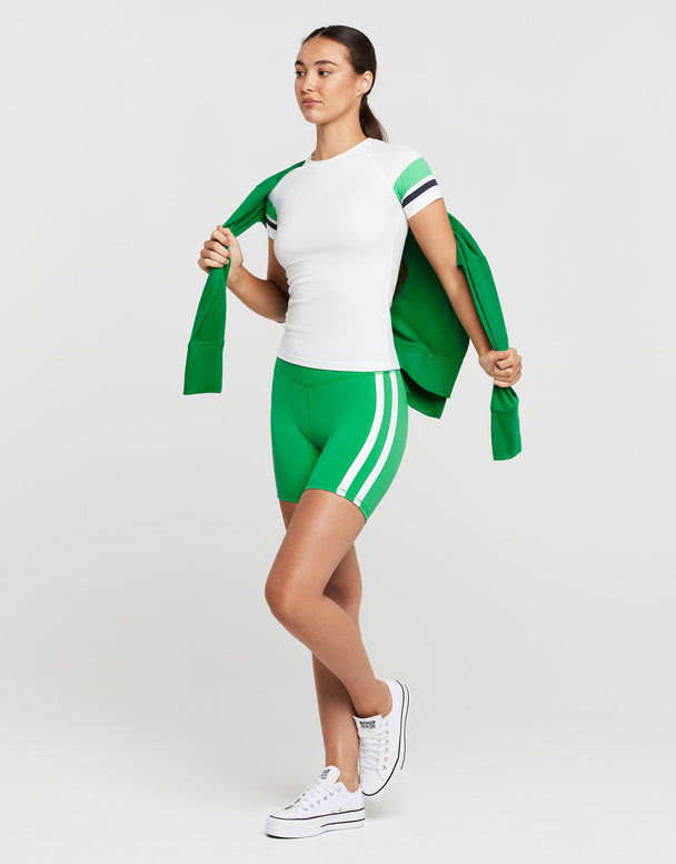 Woman wearing a green and white outfit with a jacket on a light gray background