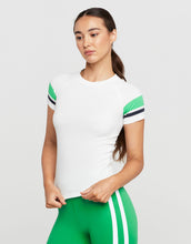 Woman wearing a white t-shirt with green sleeves and green leggings on a light gray background