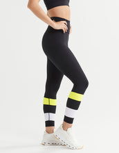Person wearing black leggings with yellow and white accents on a white background