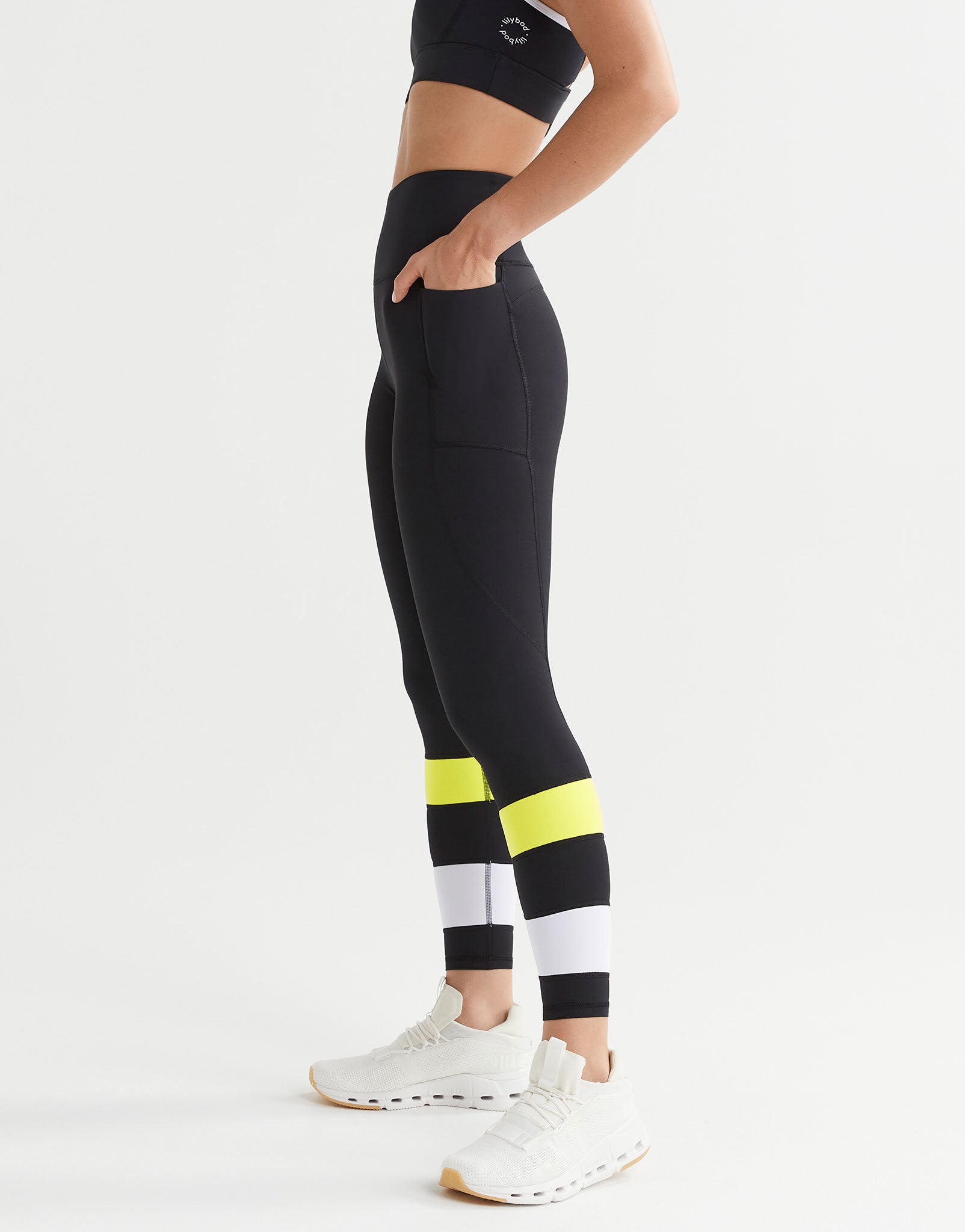 Person wearing black leggings with yellow and white striped design on a white background
