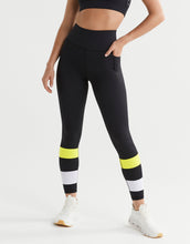 Person wearing black leggings with yellow and white accents on a white background