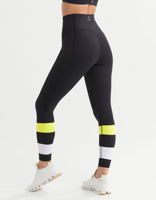 Black leggings with yellow and white accents worn by a person on a white background