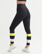 Black leggings with yellow and white accents worn by a person on a white background