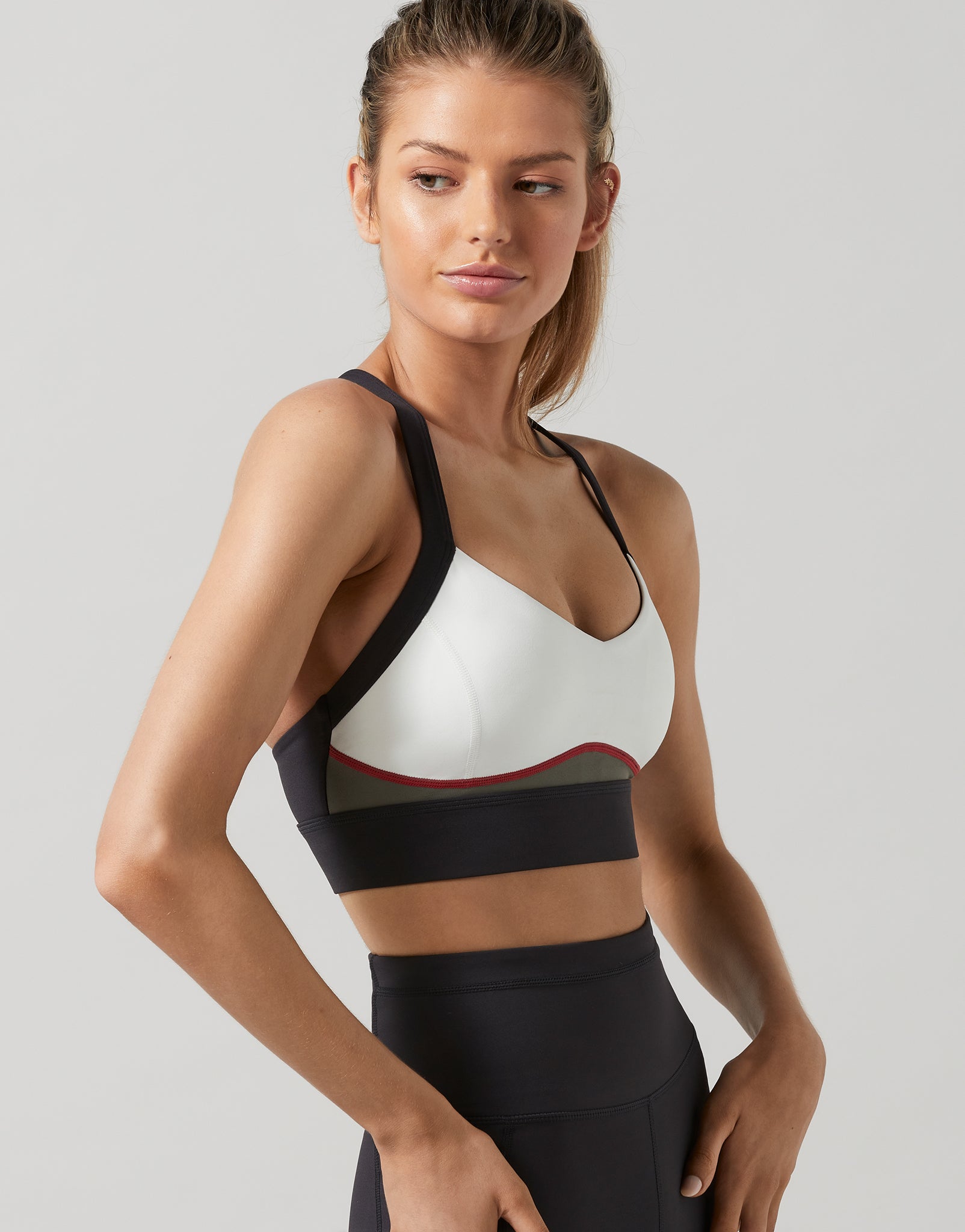A woman wearing a black, white and green colour blocked sports bra and leggings.
