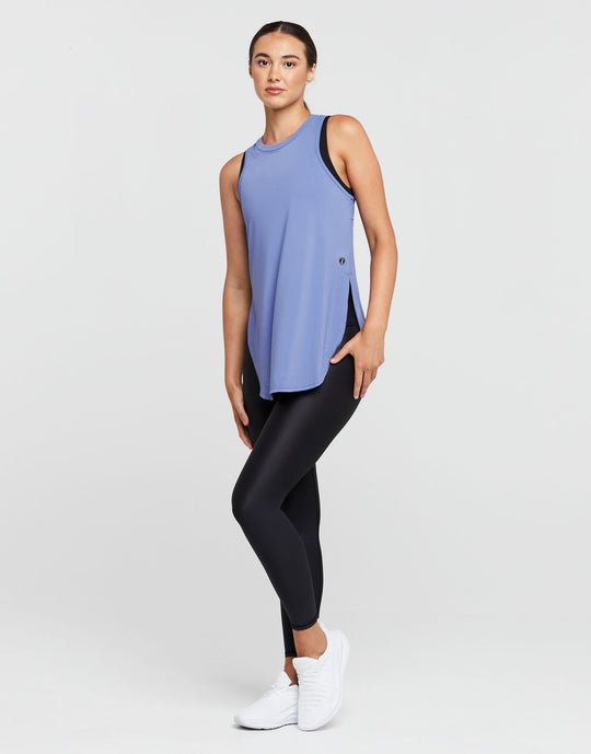 Woman wearing a blue sleeveless top and black leggings on a white background