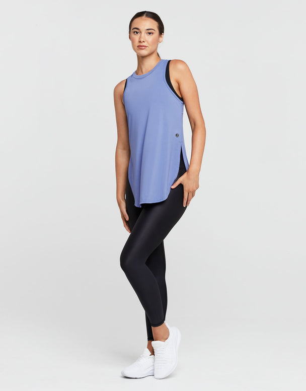 Woman wearing a blue sleeveless top and black leggings on a white background