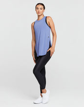 Woman wearing a blue sleeveless top and black leggings on a white background