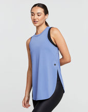 Woman wearing a blue sleeveless top with a black side panel on a light gray background
