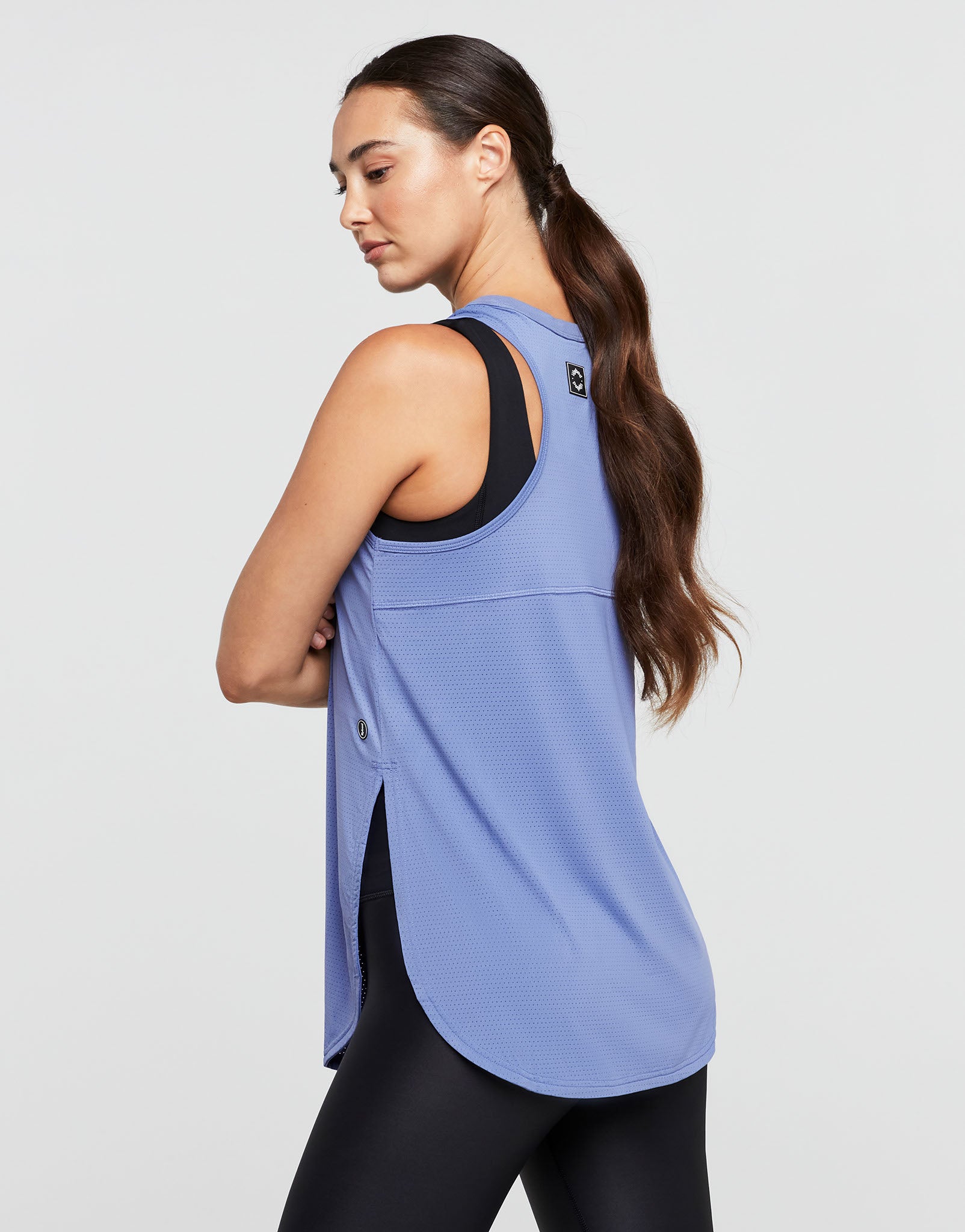 Woman wearing a blue tank top with black trim on a light gray background