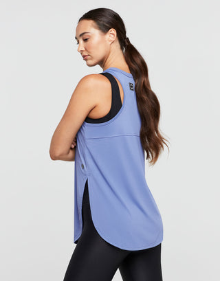 Woman wearing a blue tank top with black trim on a light gray background