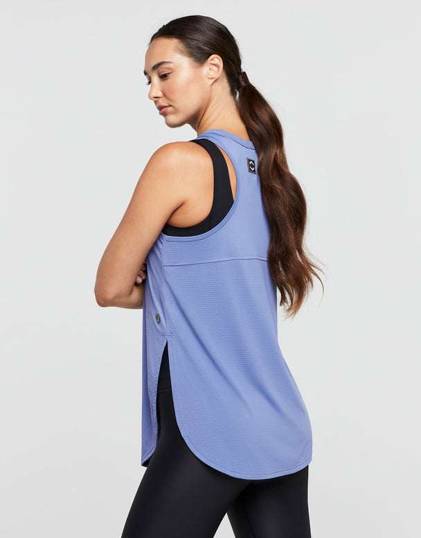 Woman wearing a blue tank top with black trim on a light gray background