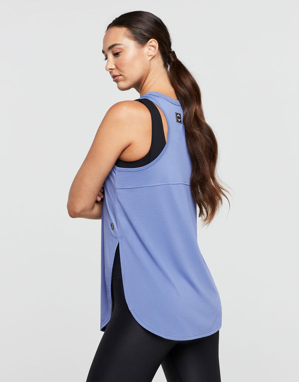 Woman wearing a blue tank top with black trim on a light gray background